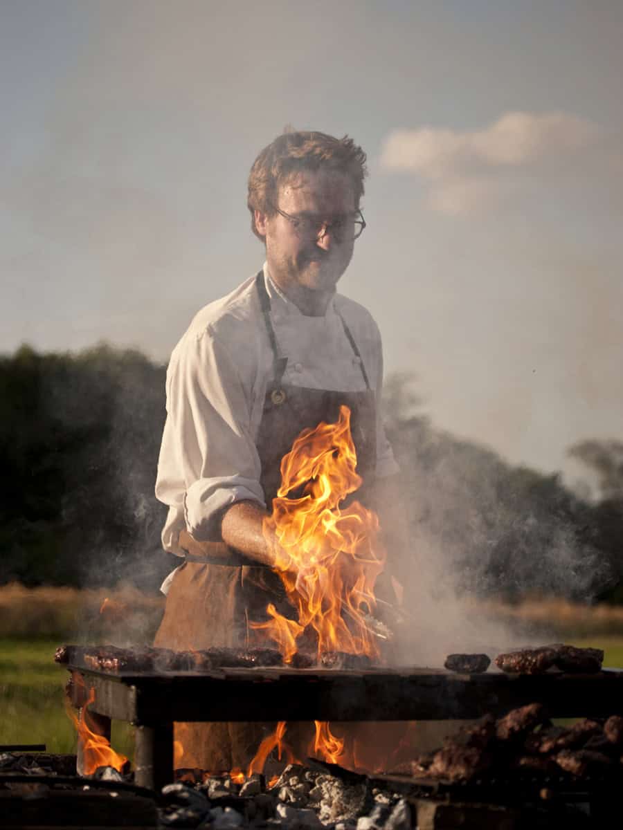 The Gillyflower open-fire cooking with chef at outdoor grill, seasonal produce at Elmore Court